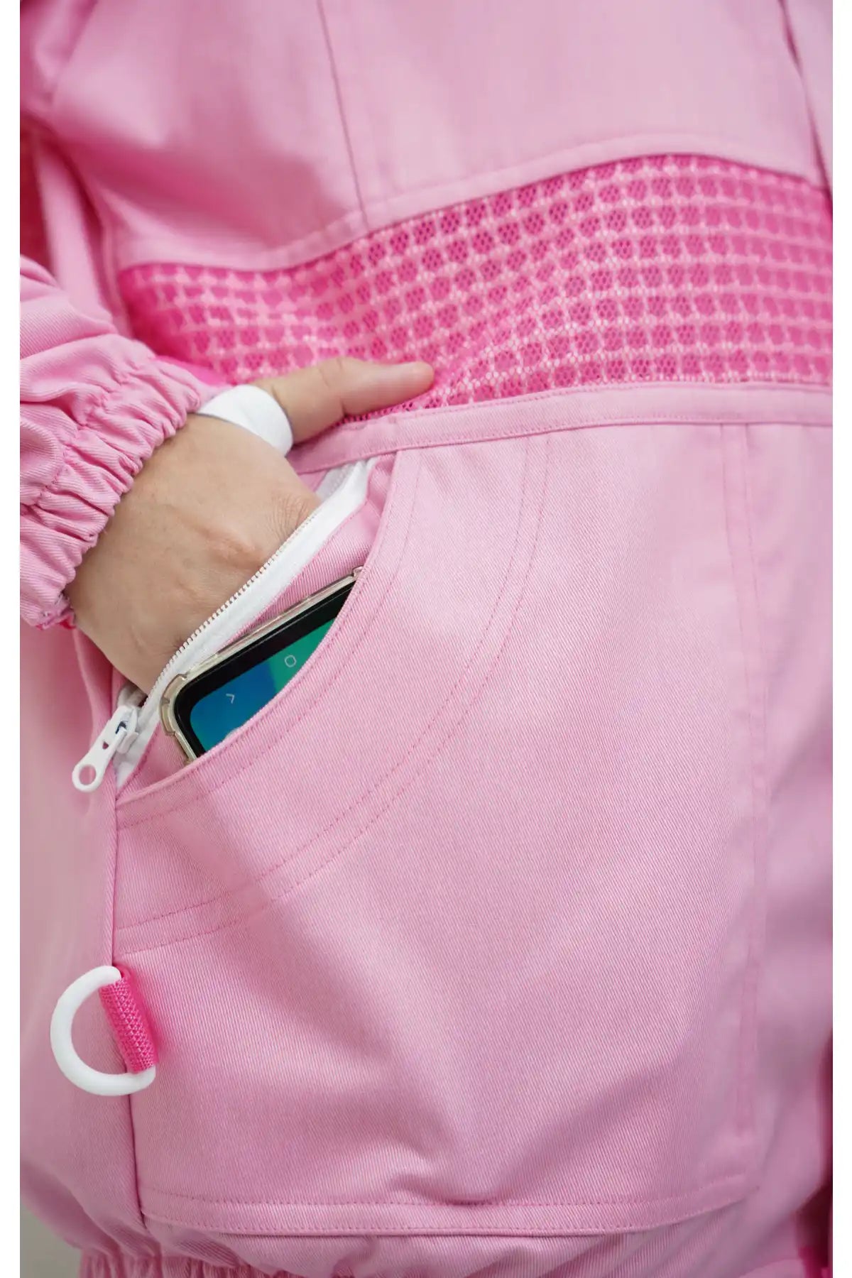 Close-up of the side zip pocket holding a smartphone on the pink poly cotton semi ventilated beekeeping jacket