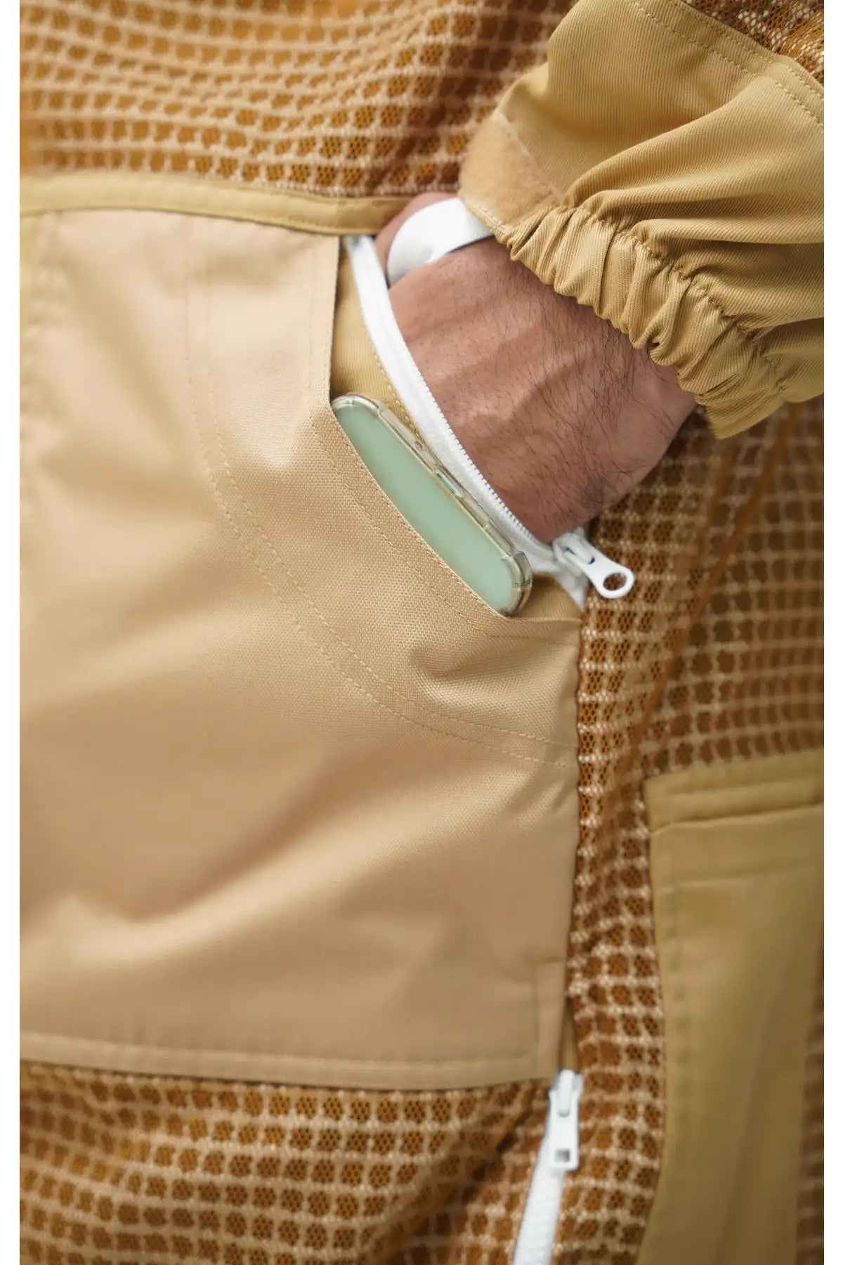 Close-up of khaki beekeeping suit zippered side pocket holding a smartphone – functional storage design for beekeepers – USA